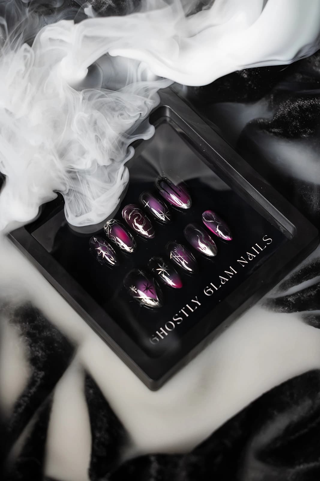 Plum chrome press-on nail set with silver flame and star detailing, photographed in smoke.