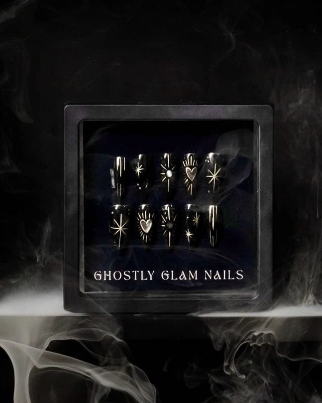 Detailed press-on nail set with hand-painted celestial designs in branded packaging.