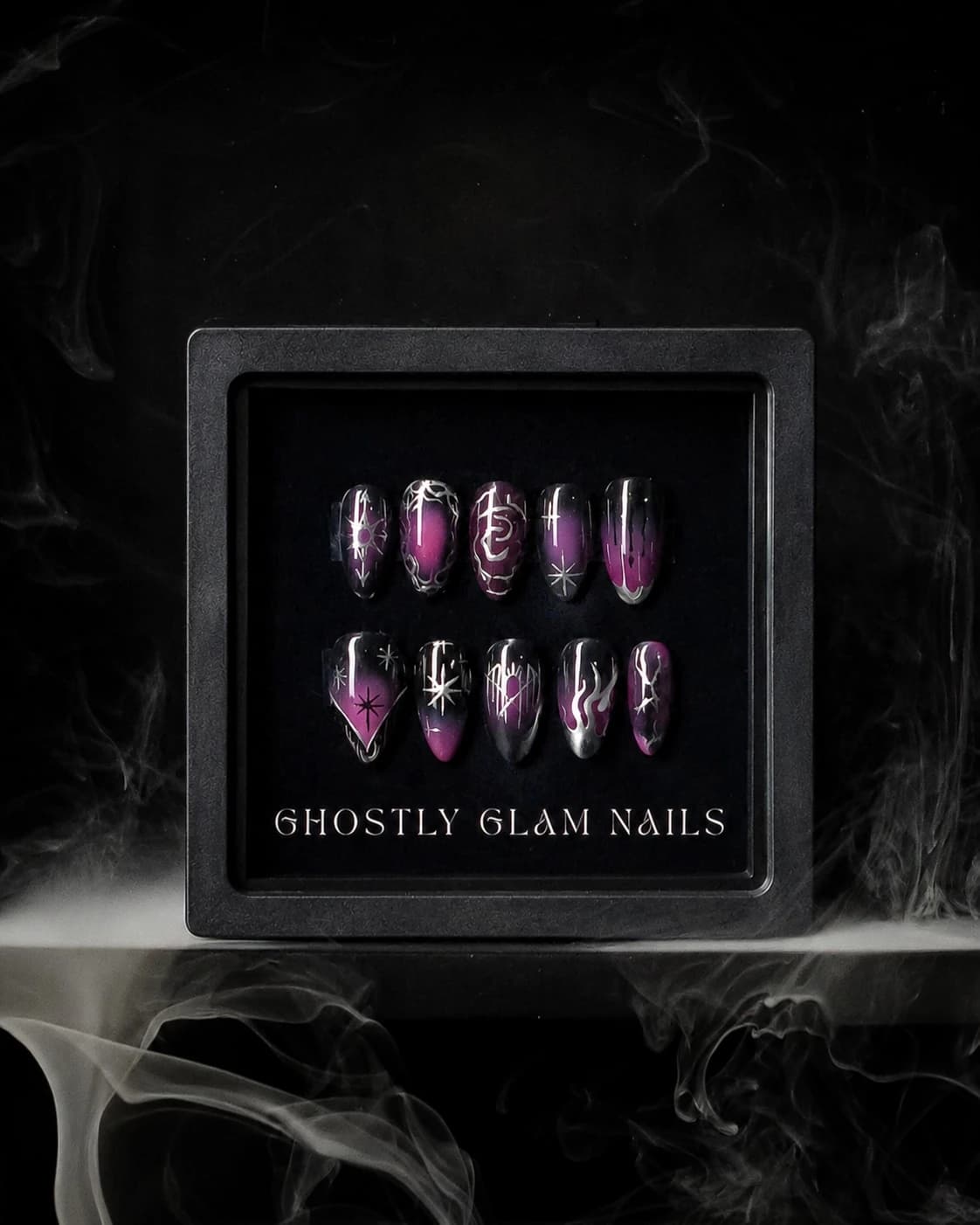 Copper press-on nail set displayed in branded packaging, surrounded by smoke.